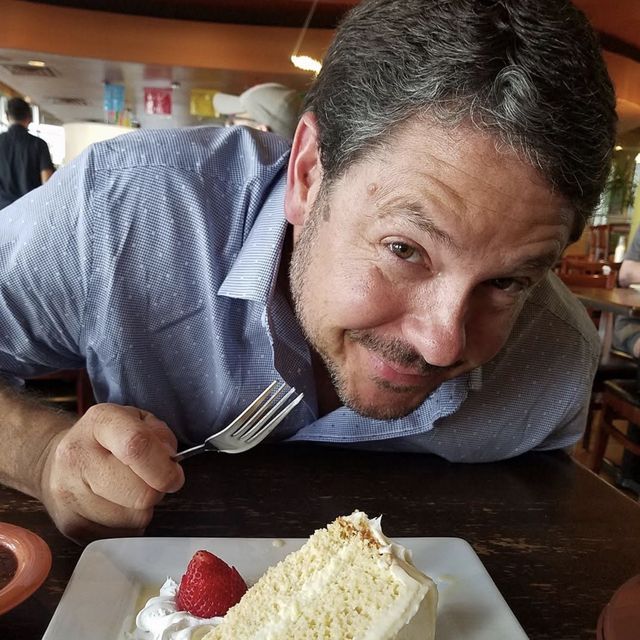 Gunny grinning over a slice of tres leches cake, fork ready